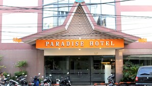 The exterior of Paradise Hotel with a prominent sign, a modern architectural design, and several parked motorcycles. - Paradise Hotel (Tanjung Pinang)