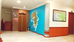A lobby with a map on the wall, a security desk, and a wooden door. - Paradise Hotel (Tanjung Pinang)
