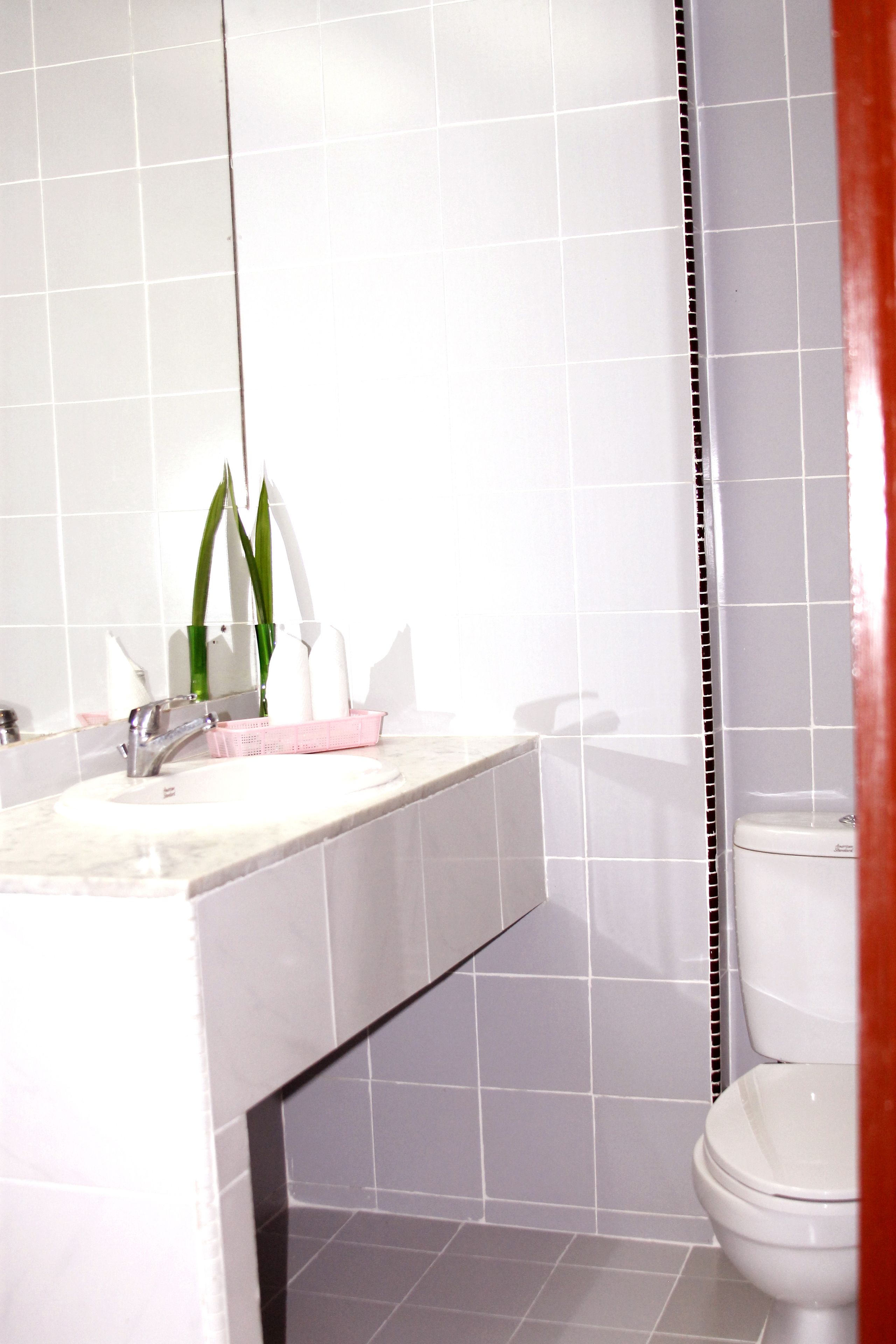 A bathroom with a white sink, mirror, and toilet.