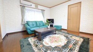Un salon avec un canapé de couleur turquoise, une table basse, un tapis à motifs floraux et une porte en bois.