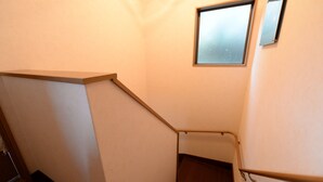 Un escalier étroit avec une rampe en bois et une petite fenêtre en haut.