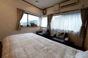 Una habitación de hotel con una cama grande, un sofá pequeño y una ventana con cortinas.
