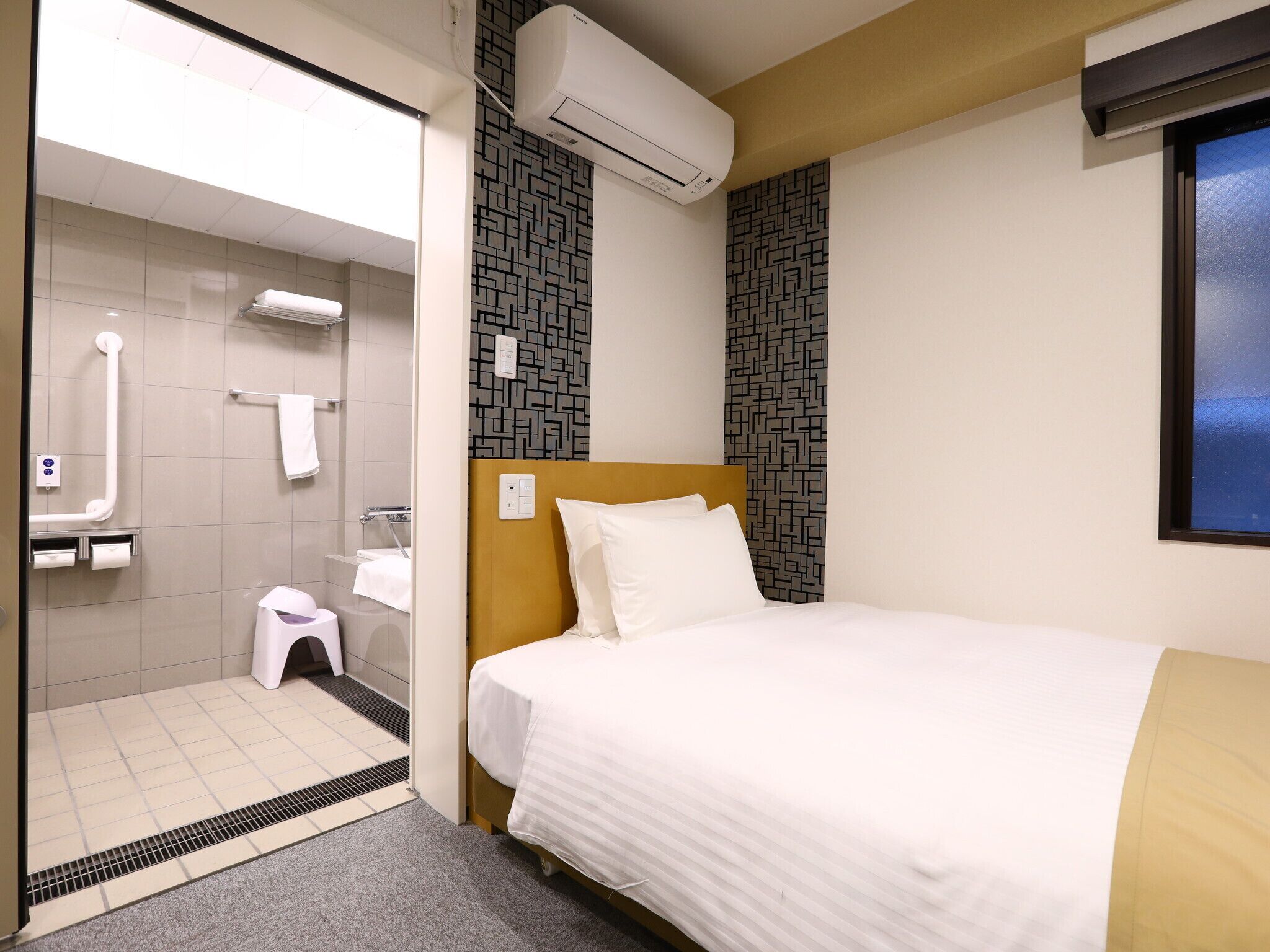 A hotel room with a bed, a shower area, and a window.