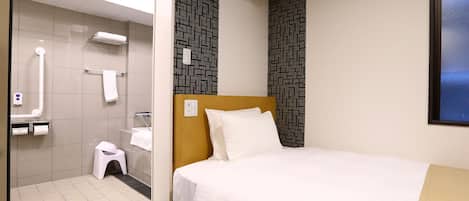 A hotel room with a bed, a shower area, and a window.