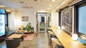 Ein moderner Lounge-Bereich mit Sitzgelegenheiten, einer Kaffeemaschine und einem großen Fenster.