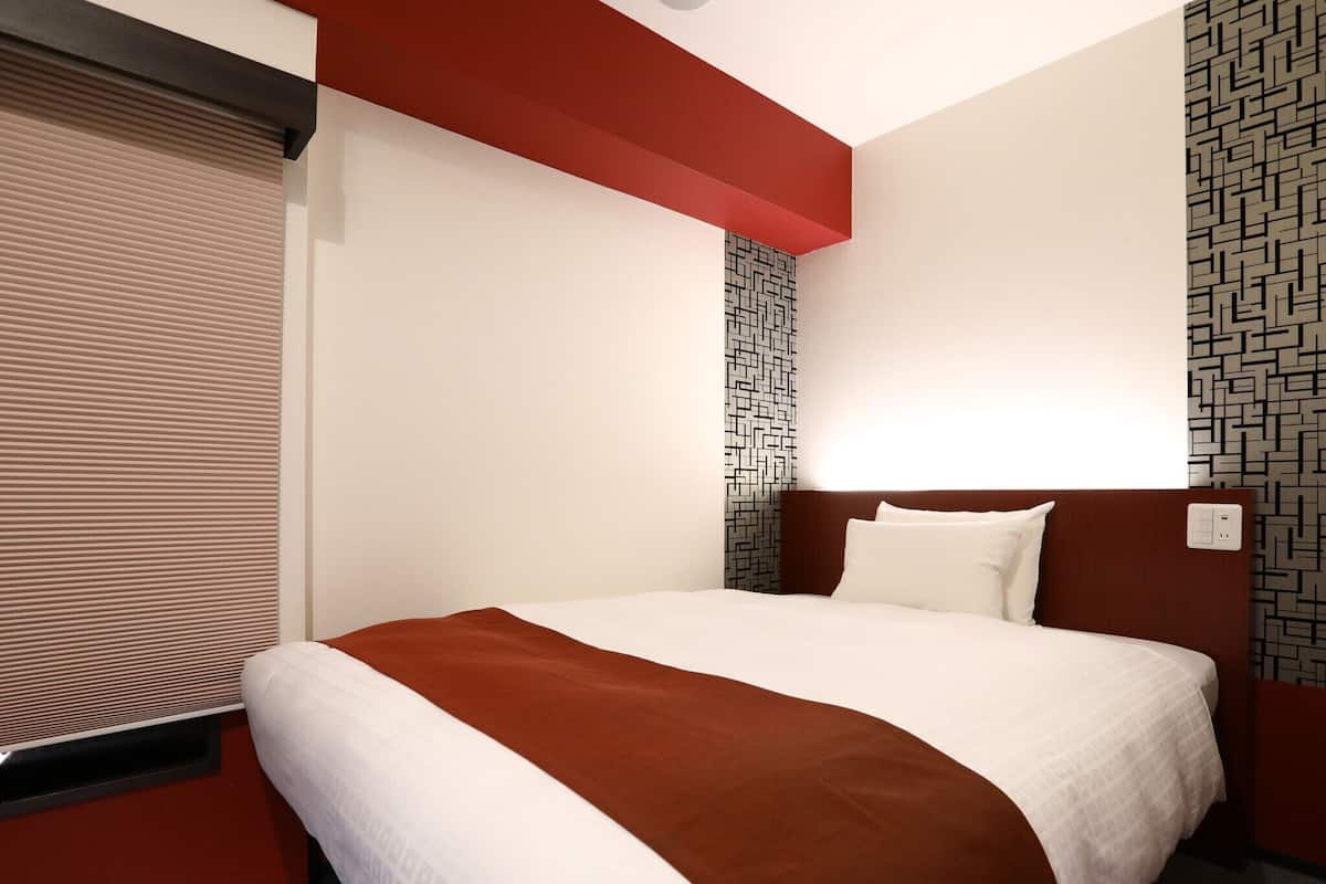 Une chambre d’hôtel avec un grand lit, un mur d’accent rouge et un papier peint à motifs.
