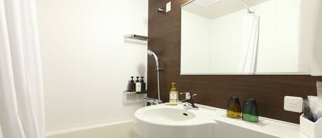 A modern bathroom with a white sink, a mirror, and a shower curtain.
