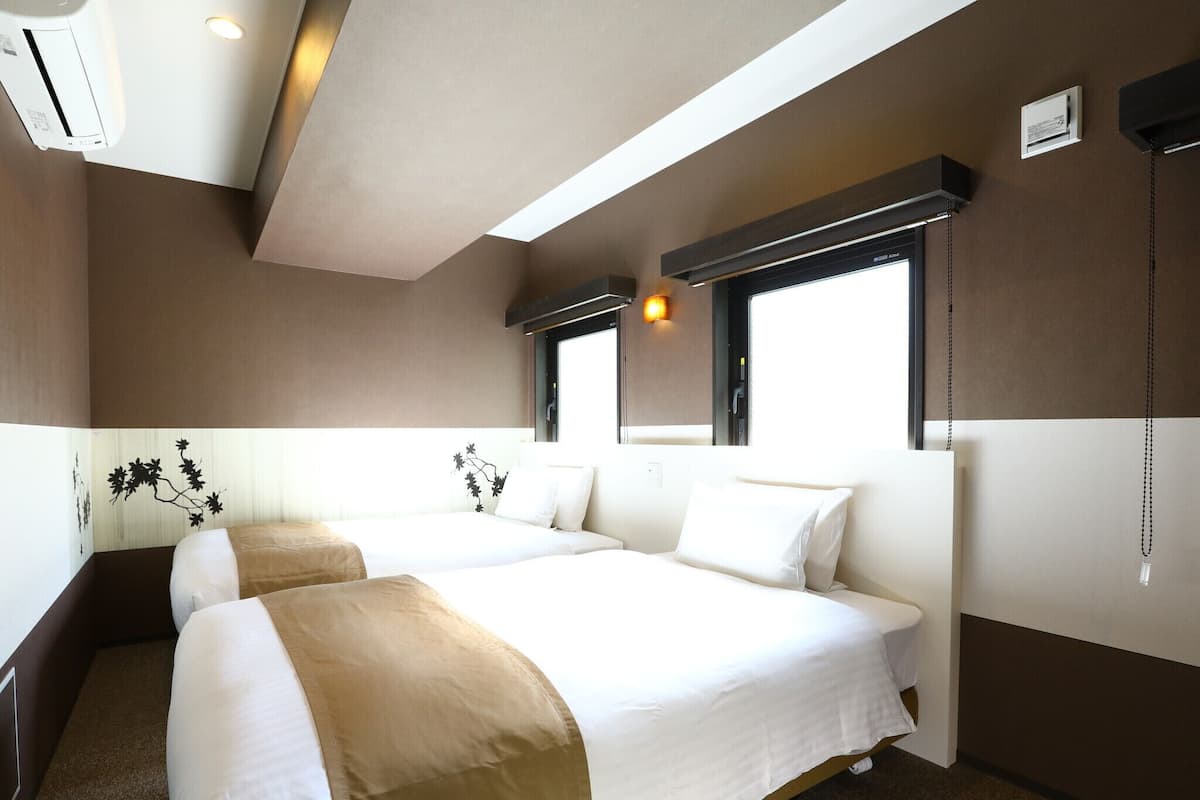 Une chambre d’hôtel avec deux lits, une fenêtre et un appareil de climatisation.