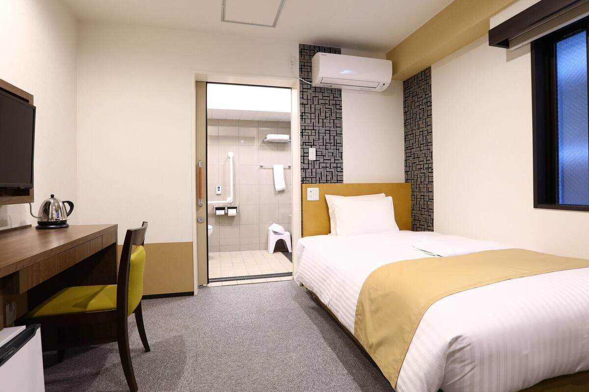 Une chambre d’hôtel équipée d’un lit, d’un bureau, d’une chaise, d’une télévision et d’un appareil de climatisation.