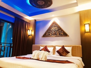 A hotel room with a bed, a decorative wall piece, and a view of the outside. - Thai Corner Hotel Patong (Patong)