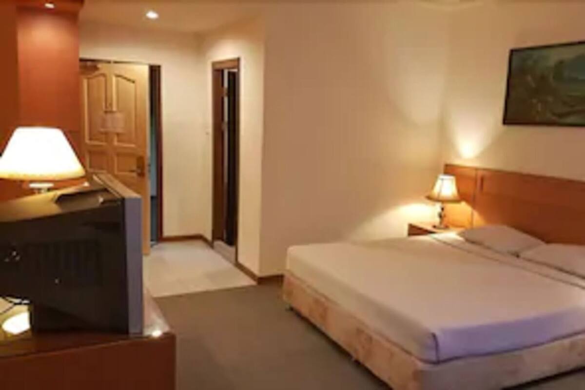 A hotel room with a bed, a television, a desk, and a painting on the wall.