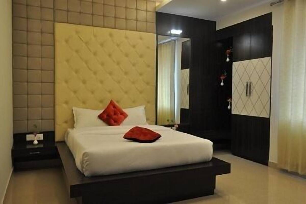 Quarto moderno com cabeceira estofada, uma cama grande, mesa de cabeceira e guarda-roupa.