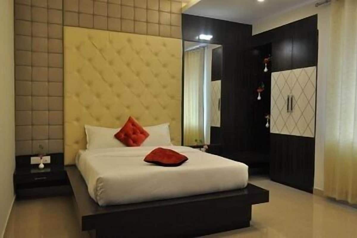 Quarto com cama, mesa de cabeceira, guarda-roupa e espelho.