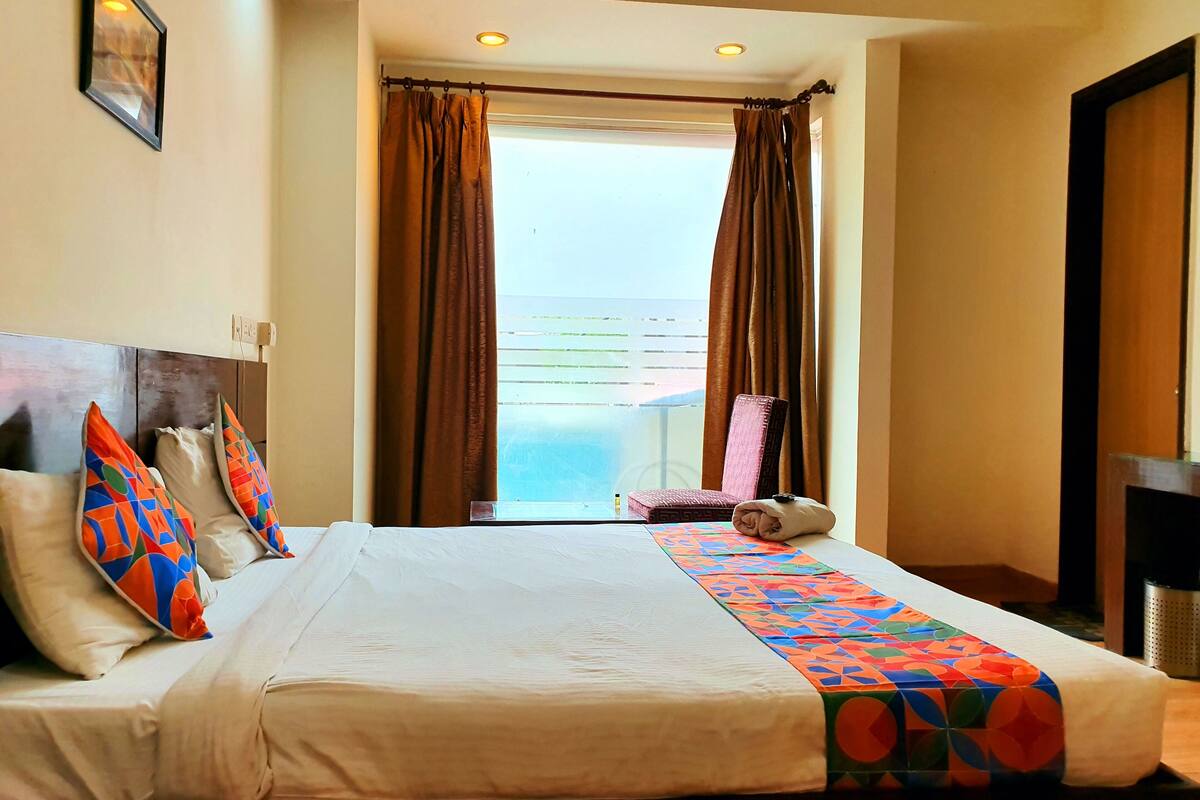 A hotel room with a bed, a chair, and a view of the outdoors.