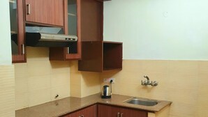 Una cocina funcional con armarios de madera, encimera, lavabo y hervidor.