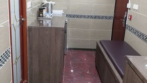 A compact kitchen with a marble floor, a wooden counter, a sink, a fan, and a door with a decorative handle. - Asia Inn (Kowloon)