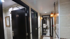 A hotel corridor with black doors, a mirror, and a bathroom visible in the distance. - Asia Inn (Kowloon)