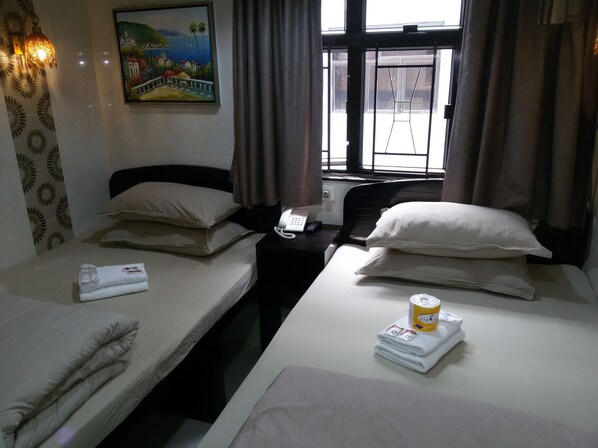 Une chambre d’hôtel avec deux lits, un tableau au mur, une fenêtre avec des rideaux et une table de chevet avec un téléphone et une télécommande.