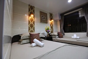 Une chambre d’hôtel avec deux lits, chacun agrémenté d’une serviette roulée, d’un vase avec des fleurs et de coussins décoratifs.