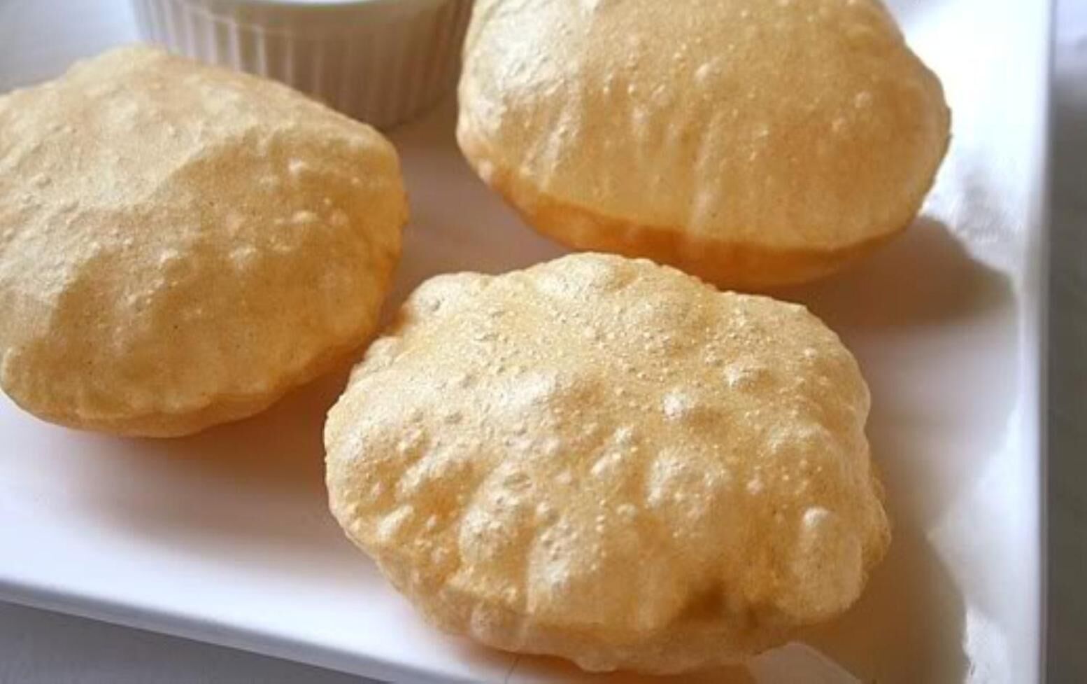 Tres pasteles redondos y dorados sobre un plato blanco.