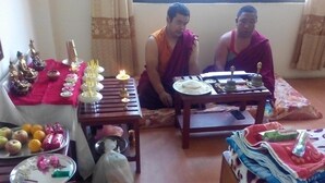 Una stanza con un tavolo apparecchiato per un pasto, una statua di Buddha e una finestra con tende.