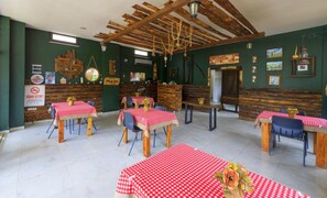 En rustik restaurang med träbjälkar i taket, rutiga bordsdukar och väggar av sten.