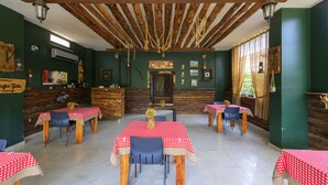 A rustic dining area with wooden beams, checkered tablecloths, and a wooden reception desk.