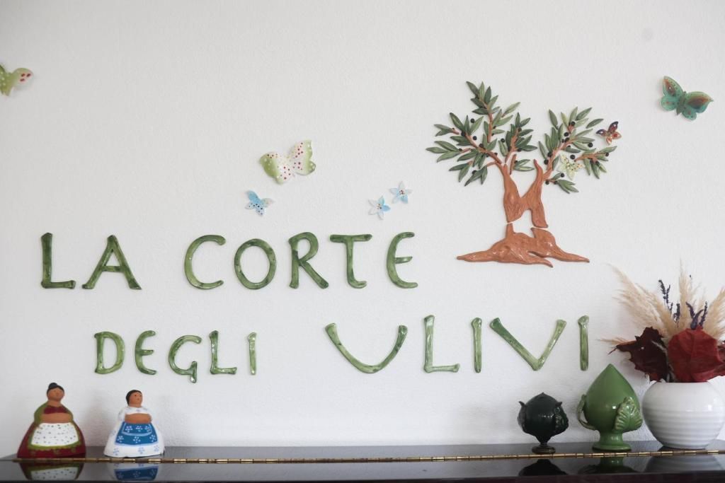 Paredes com o texto 'LA CORTEGLI VLIVI' e uma ilustração de uma árvore.