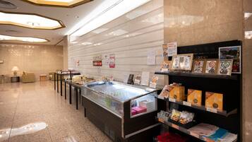 A modern hotel lobby with a reception desk, seating area, and a display of local products.