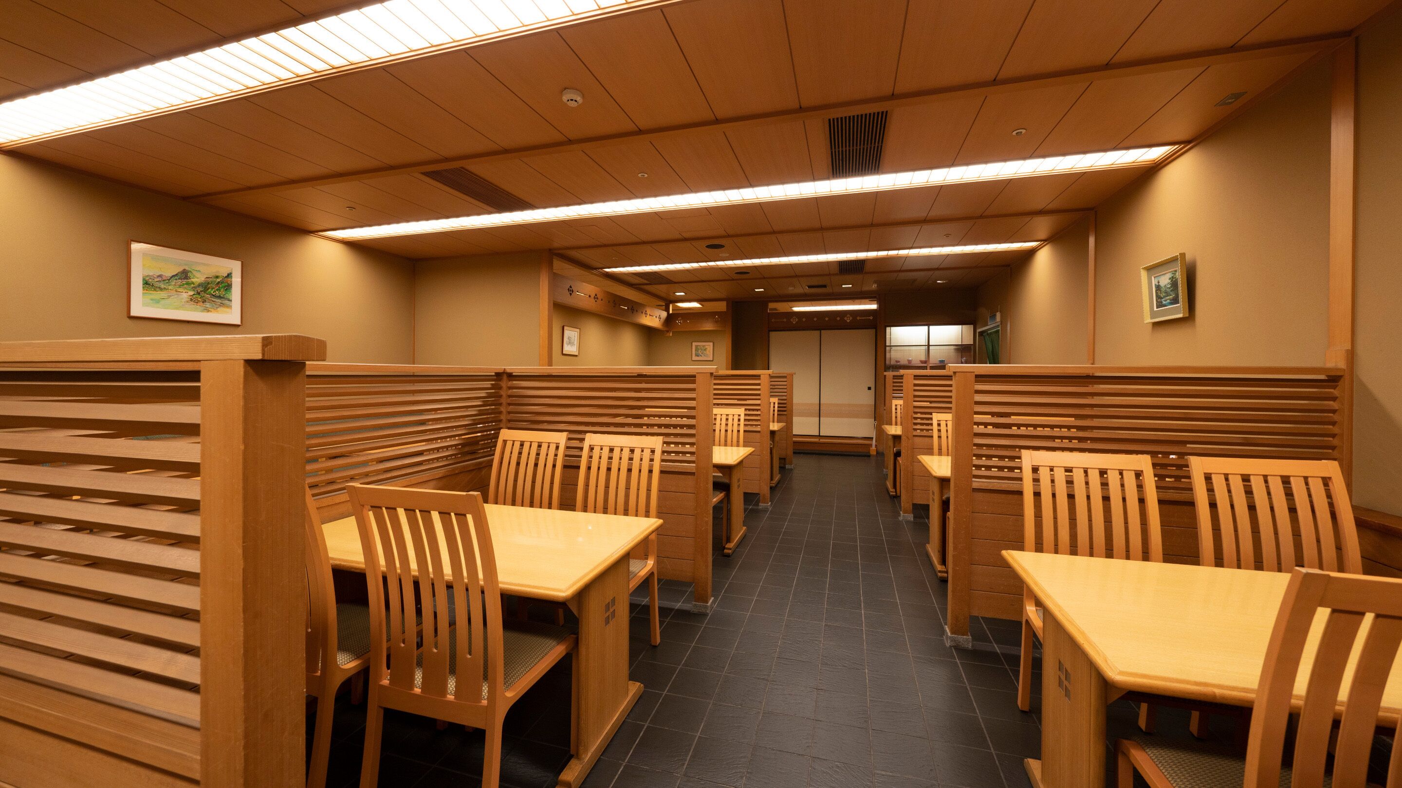 A restaurant with wooden booths and tables, a tiled floor, and framed pictures on the walls.