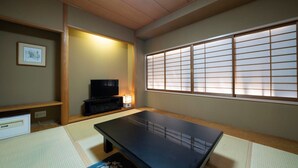 A traditional Japanese room with tatami flooring, a low table, a television, and a shoji screen. - Meitetsu Komaki Hotel (Komaki)