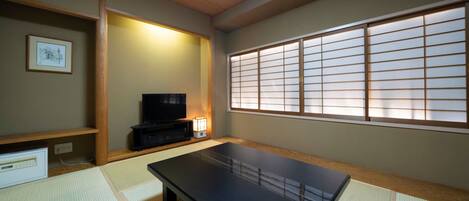 Une pièce de style japonais traditionnel, avec un sol recouvert de tatamis, une table basse, un téléviseur et un paravent en papier de riz (shoji).