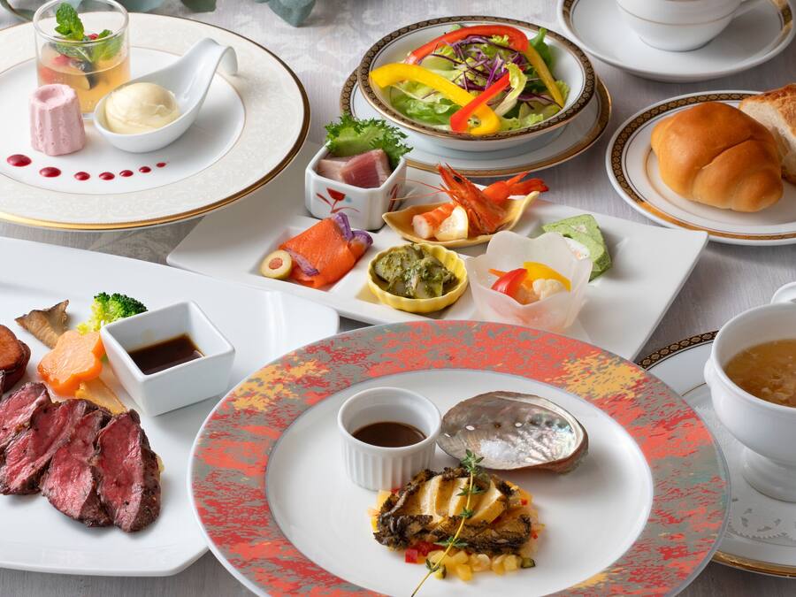A variety of dishes including steak, seafood, and vegetables, arranged on multiple plates and bowls.