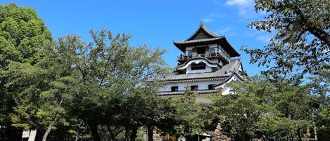 A traditional Japanese castle with multiple levels, surrounded by lush greenery and trees.