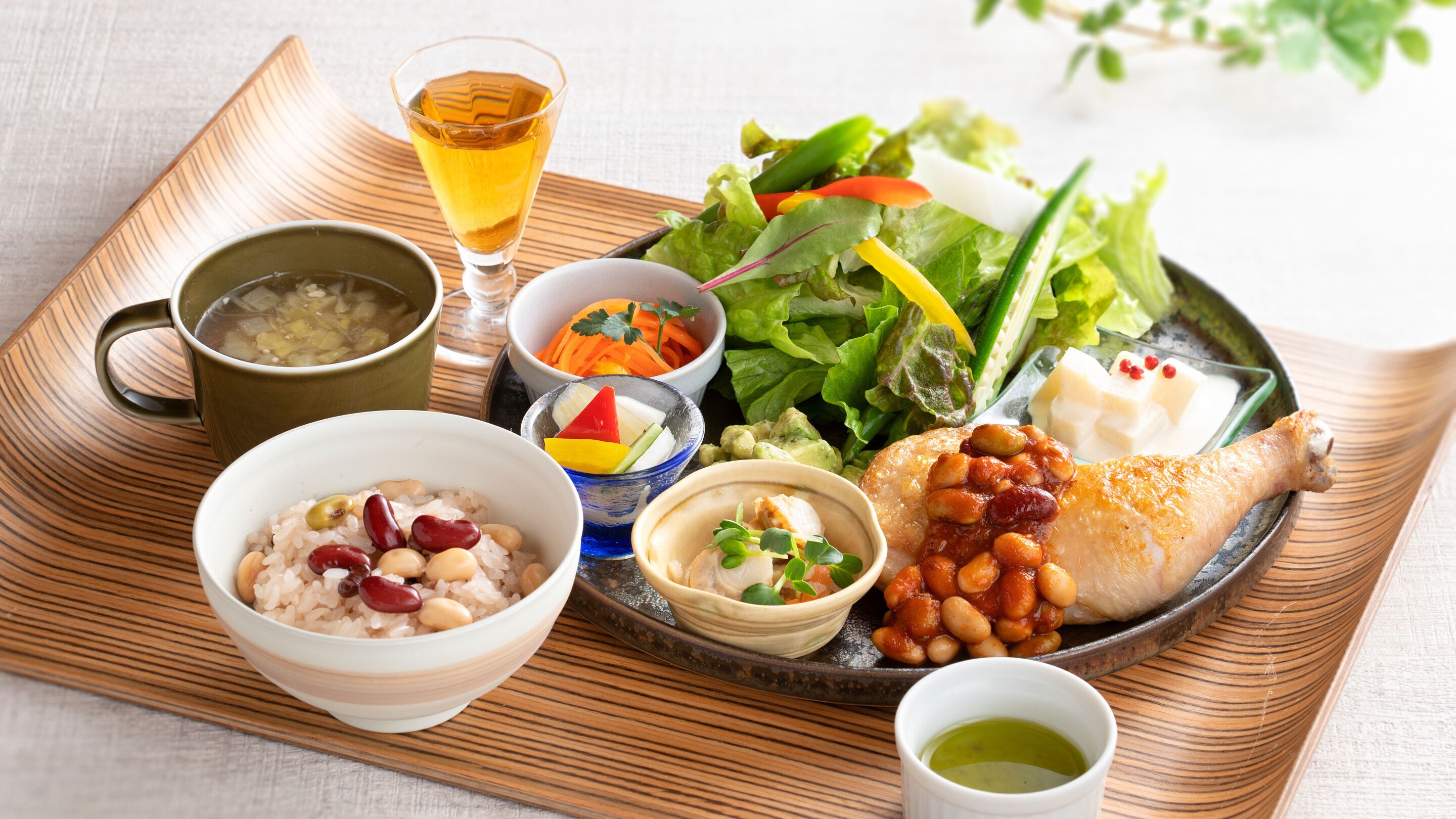 A tray with various dishes including rice, beans, a salad, and a roasted chicken leg.
