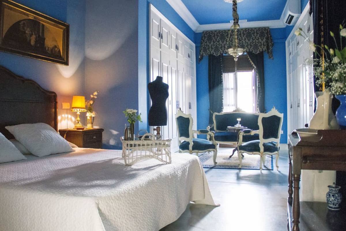 A bedroom with a bed, bedside table, lamp, dresser, and a chair.