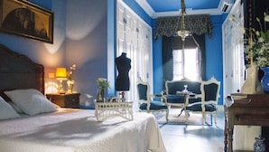 A bedroom with a bed, bedside table, lamp, dresser, and a chair.