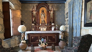 A chapel with a wooden altar, floral arrangements, and two chairs.