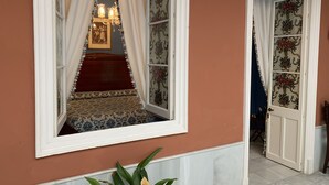 A room with a large mirror, a red carpeted area, and a door with floral wallpaper.