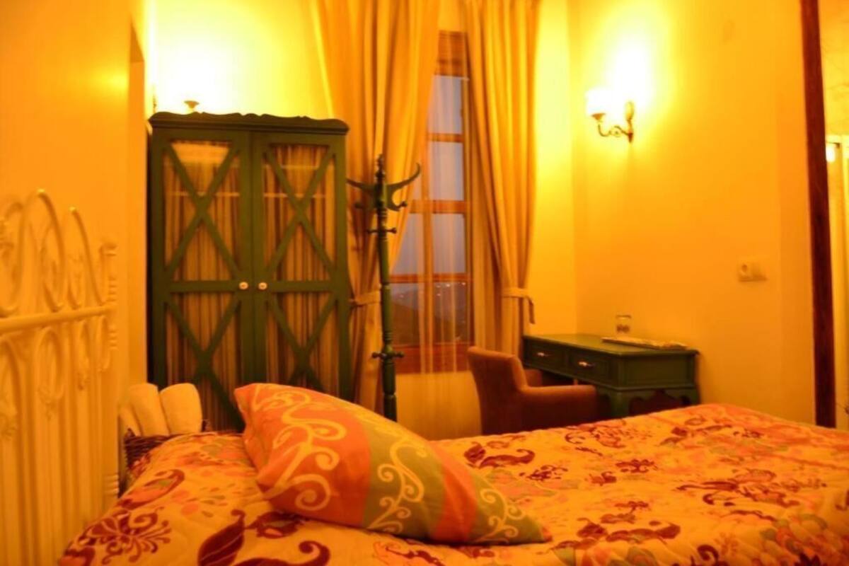 A room with a bed, a desk, a chair, a wardrobe, and a window with curtains.