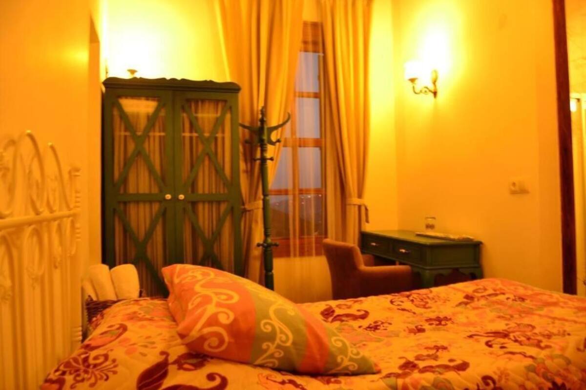 A bedroom with a bed, a green wardrobe, a desk, and a chair.