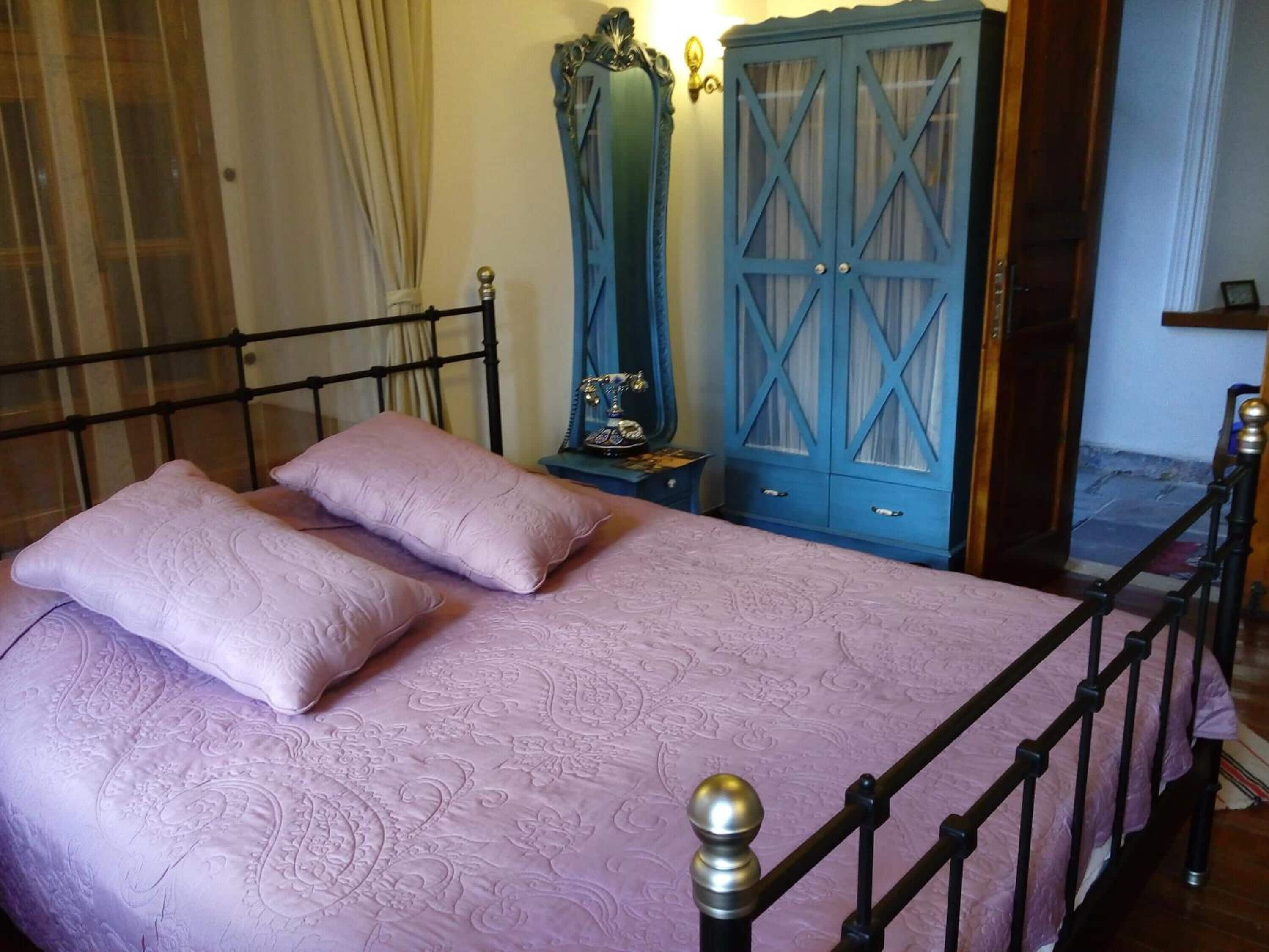 A bedroom with a bed, two pillows, a wardrobe, and a nightstand.