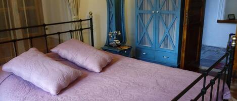 A bedroom with a bed, two pillows, a wardrobe, and a nightstand.