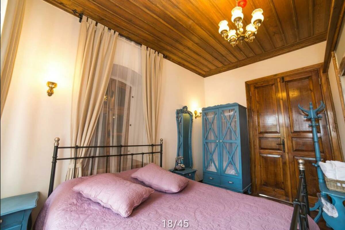 A bedroom with a bed, a wooden wardrobe, a blue cabinet, and a wooden door.