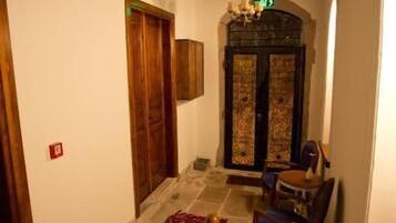 A wooden staircase leading to a room with a patterned carpet, a chandelier, and a door with intricate designs.