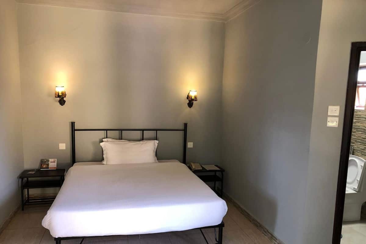 A bedroom with a bed, two bedside tables, and wall-mounted lights.