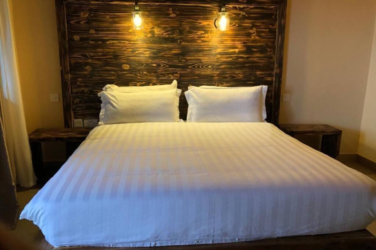 A bed with a wooden headboard, two bedside tables, and two wall-mounted light fixtures.