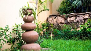 A garden with a tiered stone planter and lush greenery. - Meley Impala Hotel (Kampala)