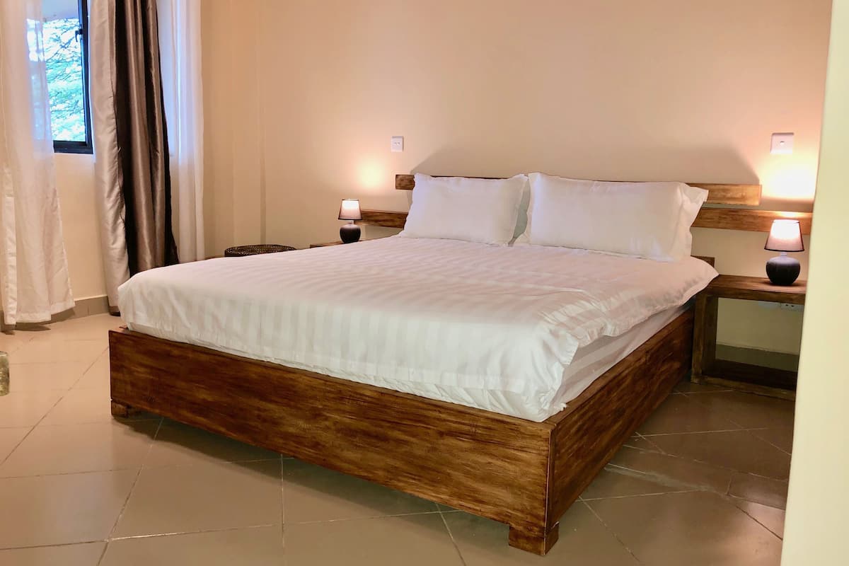 A neatly made bed with white linens in a room with wooden headboards and nightstands.
