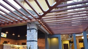An outdoor area with a wooden pergola, a reception desk, and a stone pillar. - Meley Impala Hotel (Kampala)